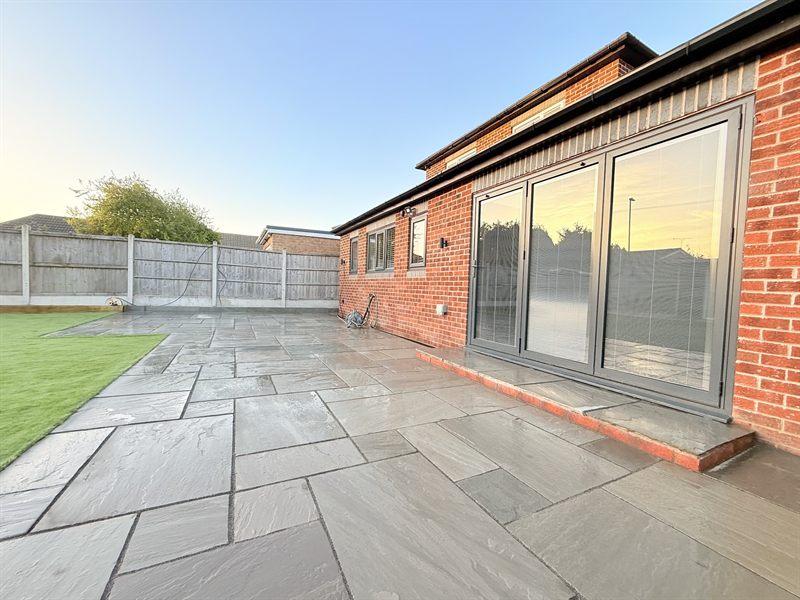 Indian sandstone patio laid up to bifold doors on a brick house.