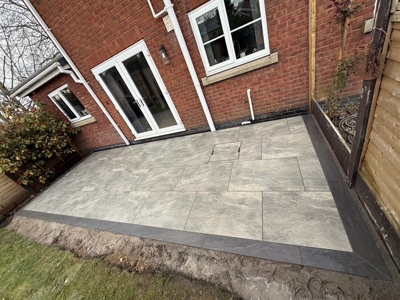 Grey patio with a dark contrasting border against a red brick house.