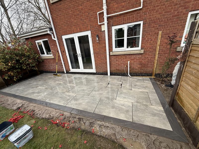 Grey paving laid outside french doors with a dark edging course.