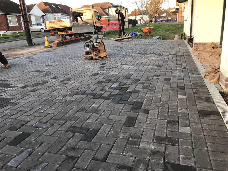 Charcoal block paving being compacted with a plate compactor.