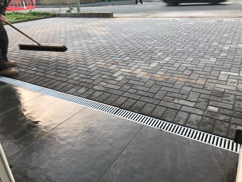 Block paving meeting a concrete apron with a linear drainage channel between.