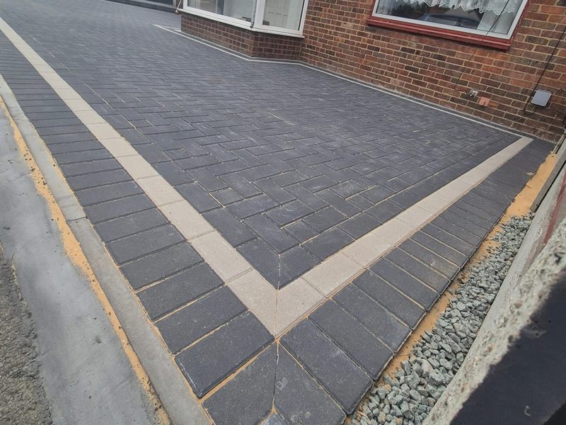 Tarmac driveway with a block-paved border running alongside a house.