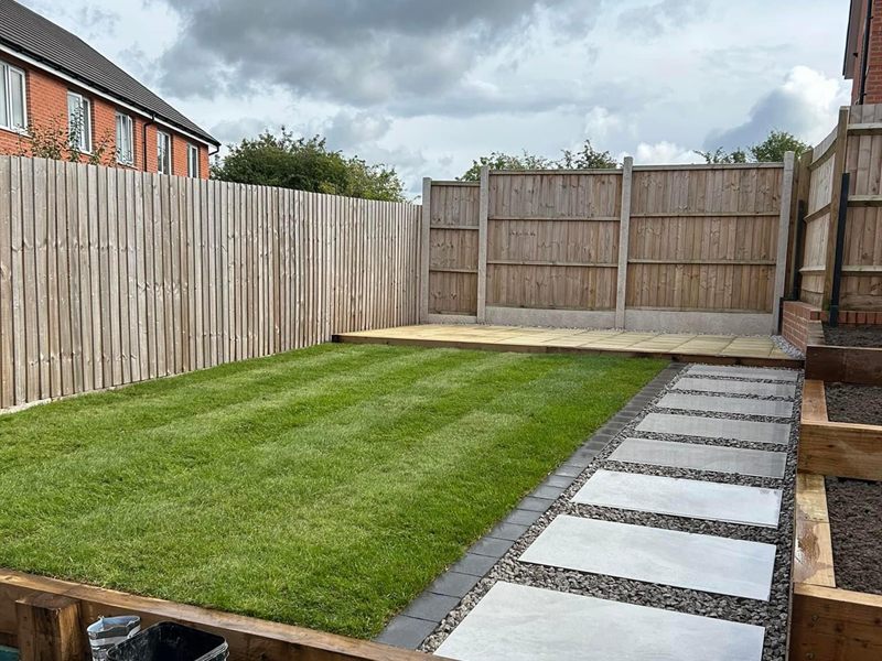 Freshly laid turf with square paving slabs set into gravel as a path.
