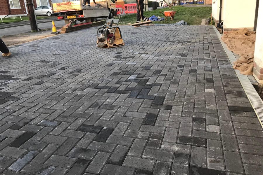 Charcoal block paving driveway being compacted with a plate compactor.