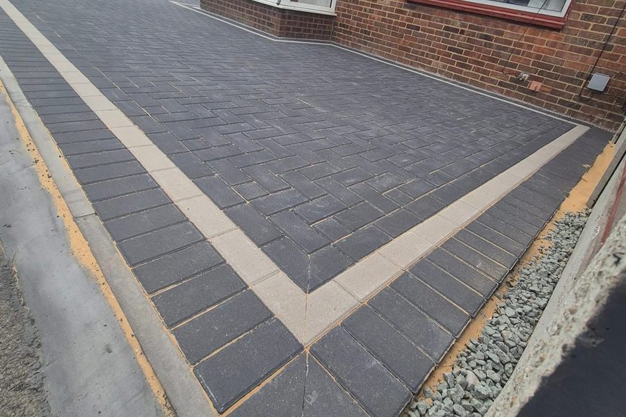 Tarmac driveway with a block-paved border running alongside a house.