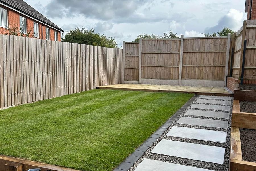 Freshly laid turf with square paving slabs set into gravel as a path.