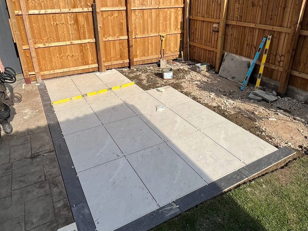 New timber fence panels behind a freshly laid pale porcelain patio.